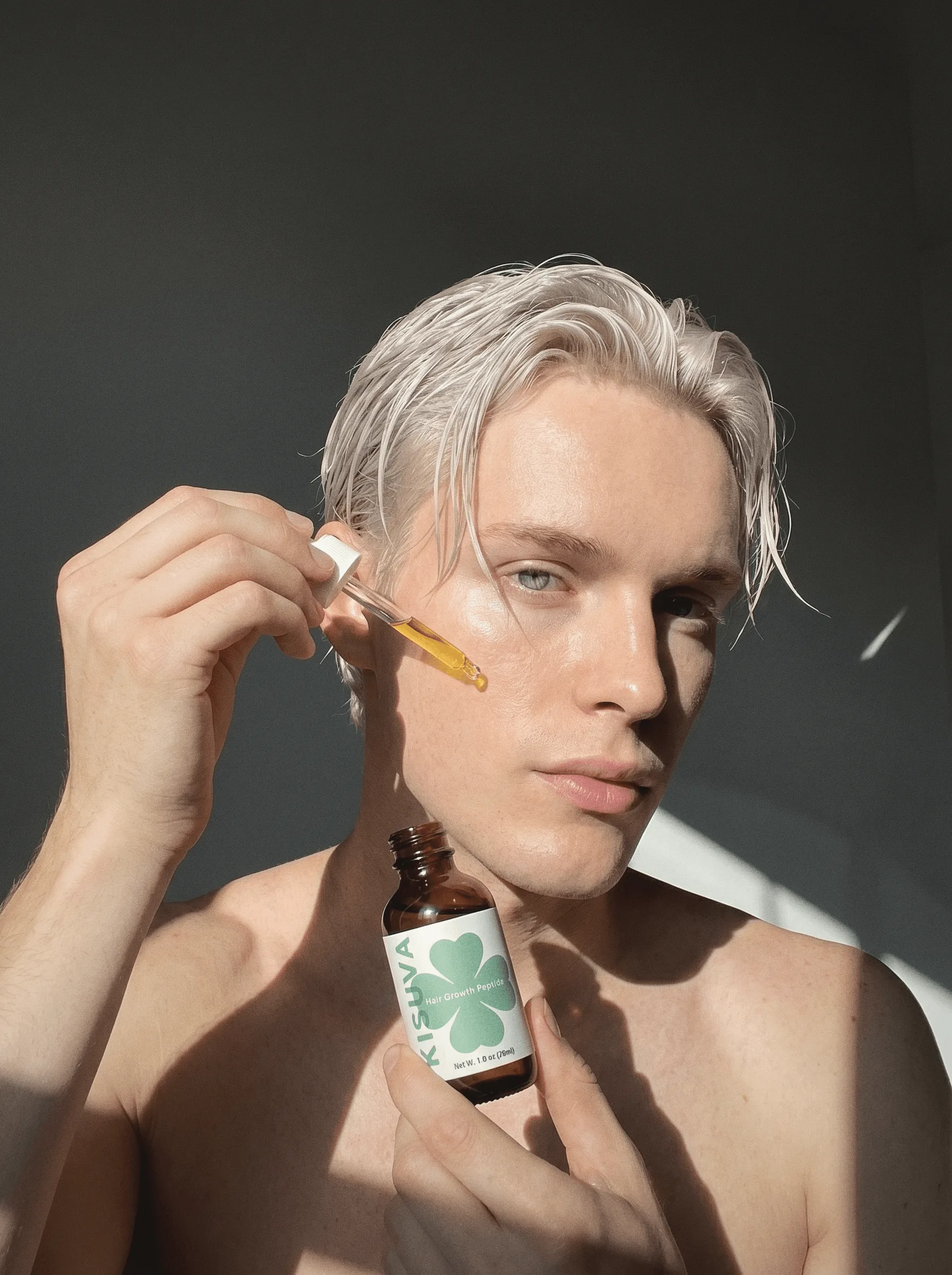 Blonde man applying Kisuva Hair Growth Serum