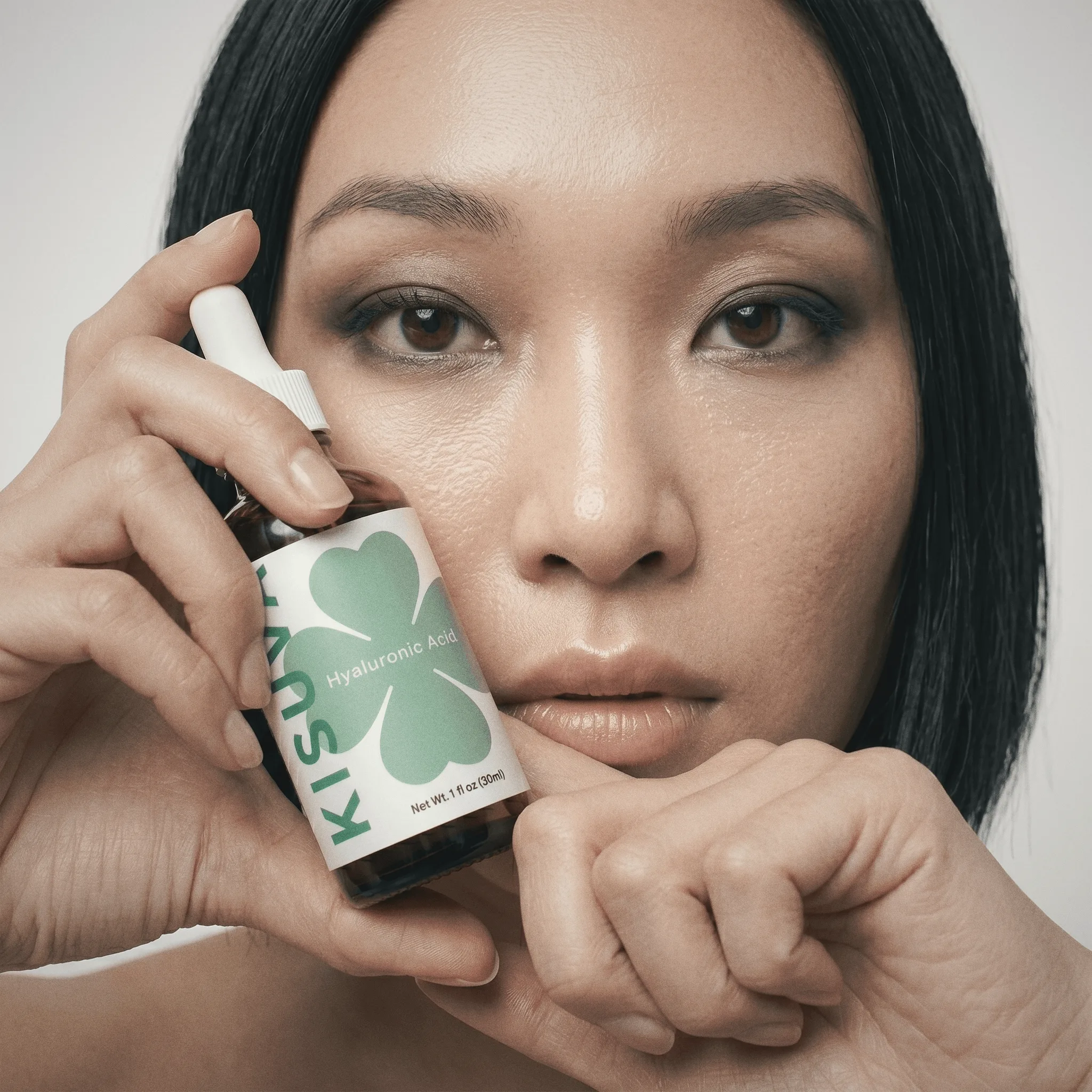 Woman applying Kisuva Hyaluronic Acid Serum to forehead
