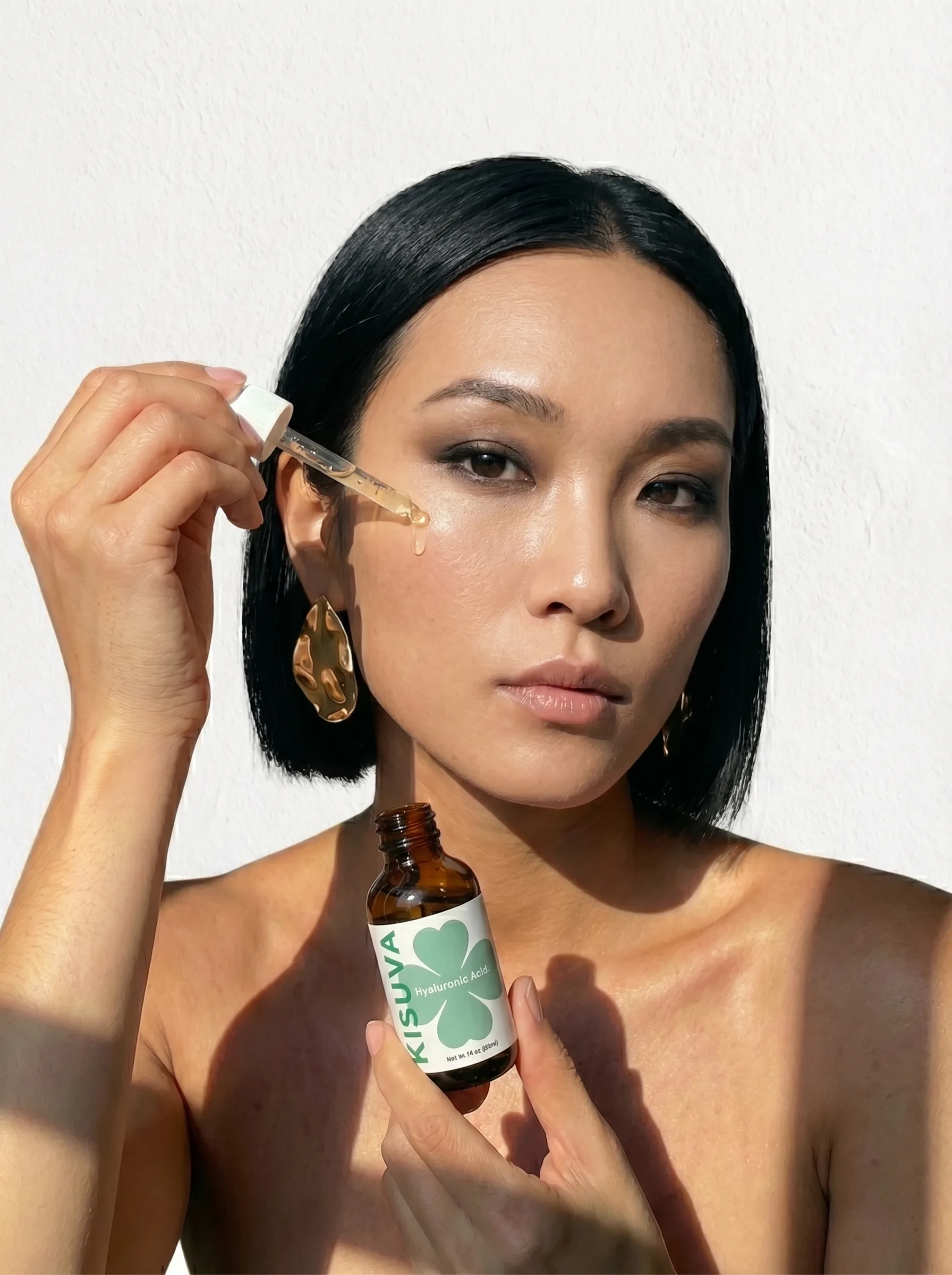 Woman applying Kisuva Hyaluronic Acid Serum with dropper