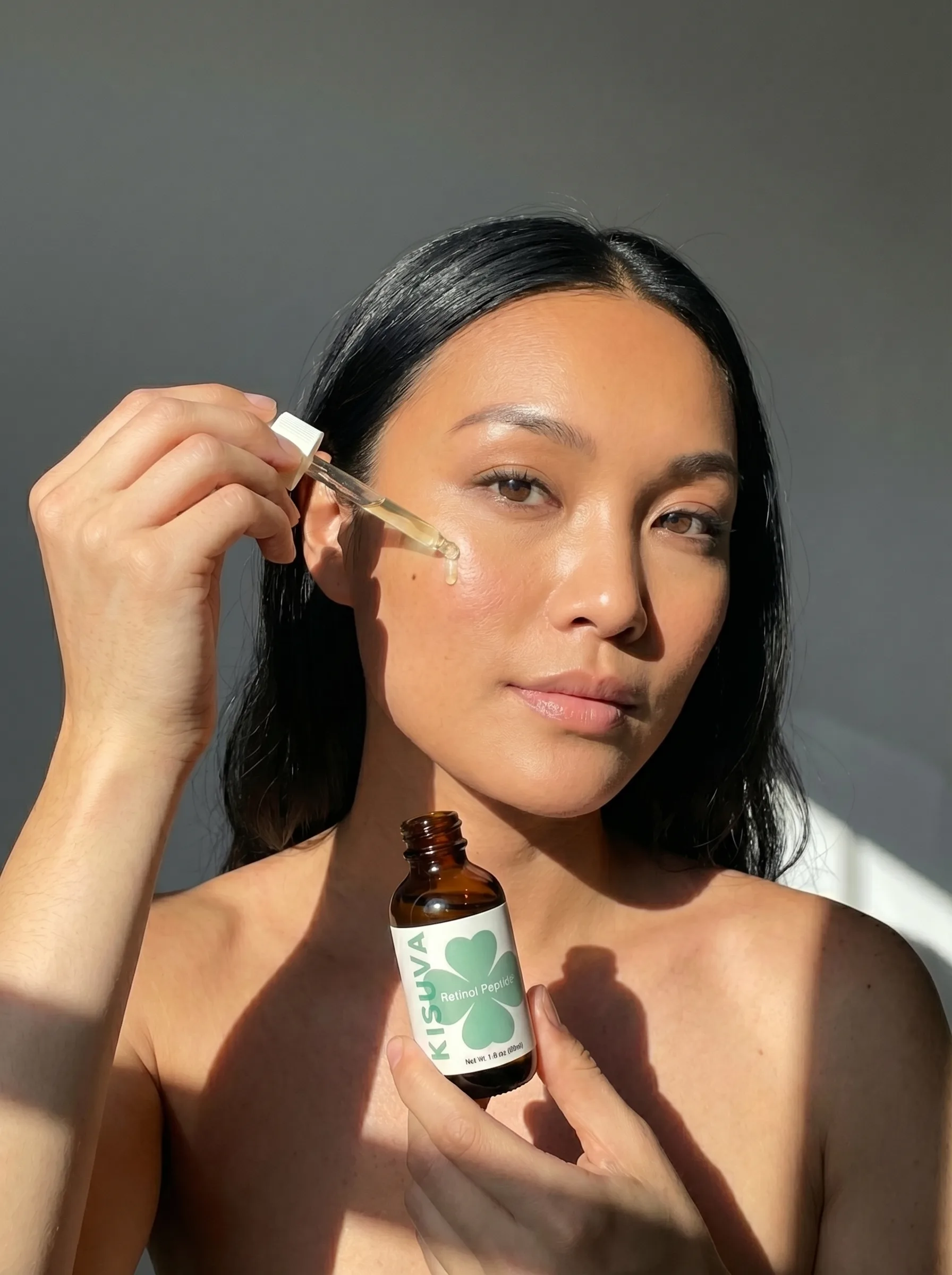 Woman applying Kisuva Retinol Serum with dropper